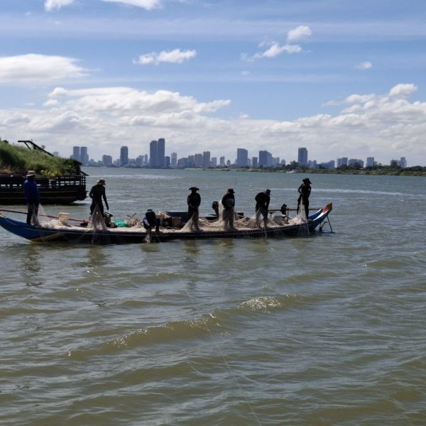 Fisher man are catch the fish in Tonle Sab with the view of city Phnom Penh background.